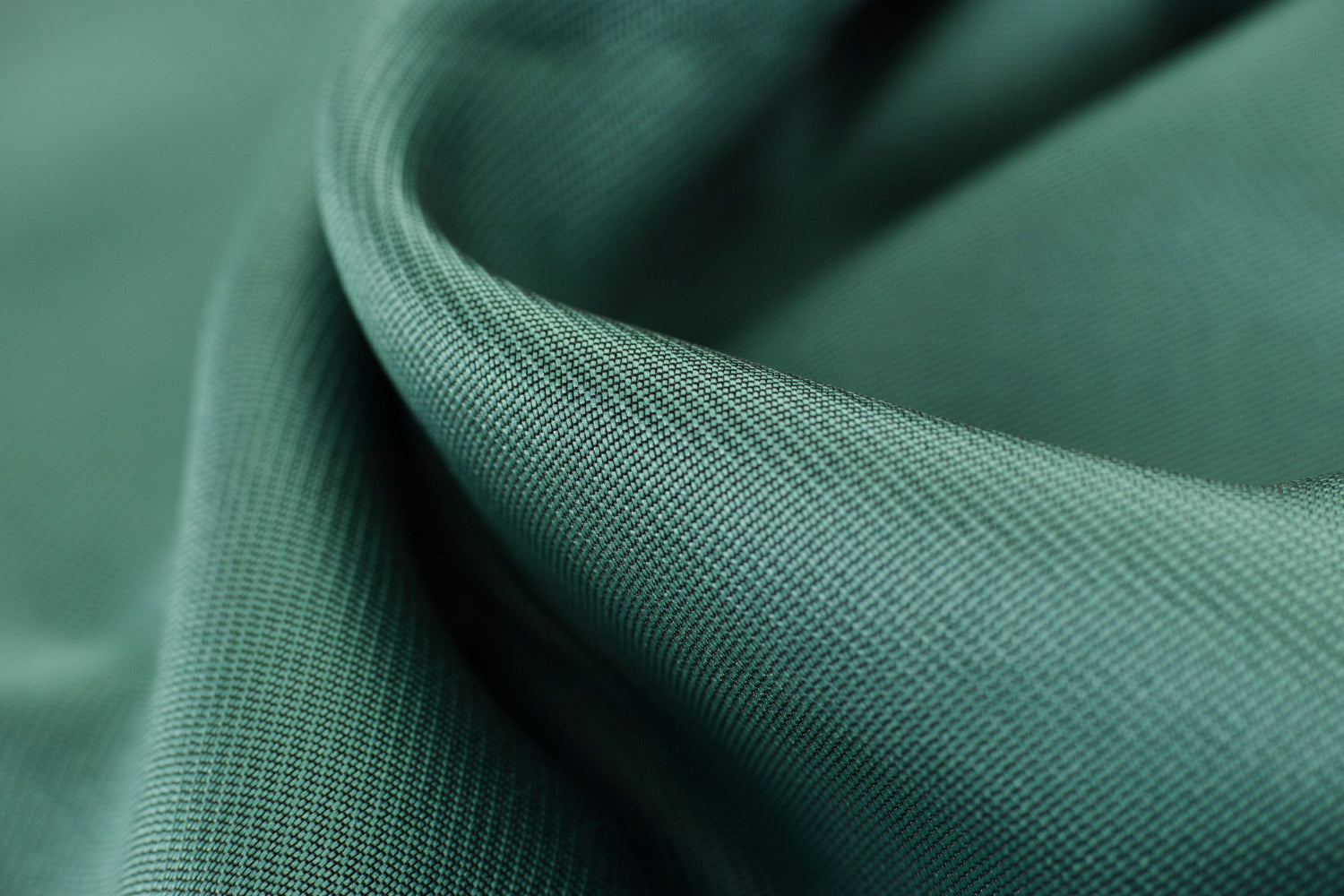 Detailed macro shot of smooth green fabric fibers showing weave pattern, used to compare texture quality in tencel vs cotton