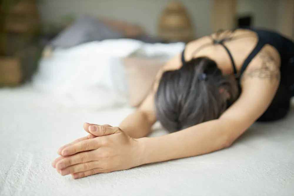 A woman practicing bedtime yoga with gentle poses in a softly lit room designed for relaxation and restful sleep.
