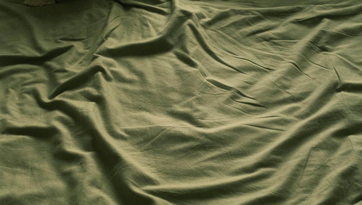 Green bedding with pillows arranged on a bed to illustrate certified fabric and natural bedding materials.