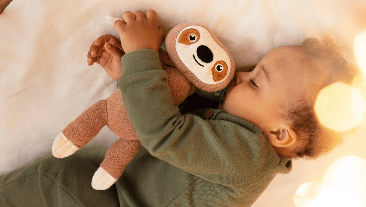 Baby sleeping comfortably while holding a soft plush toy, dressed warmly for a safe and cozy winter night.