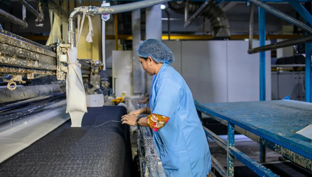 Worker operating machinery during fabric production in a textile factory.