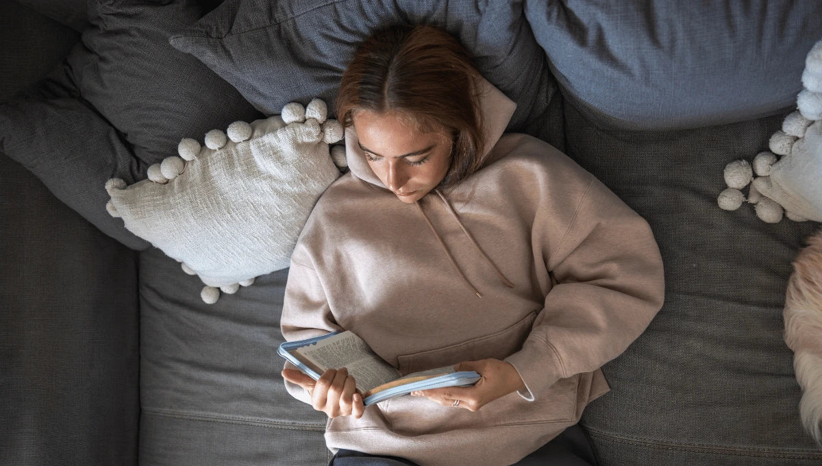 Woman wrapped in a chunky knit blanket at home, creating a calm and cozy winter wellness moment.
