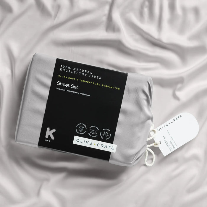 Olive & Co. sheet set packaging on a textured fabric background #color_gray mist