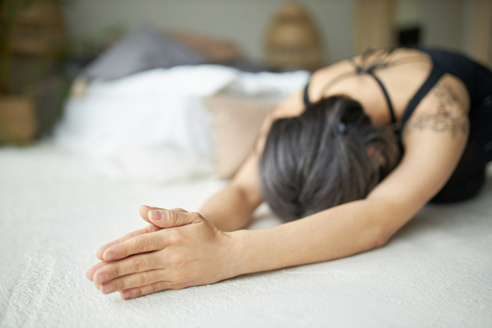 A woman practicing bedtime yoga with gentle poses in a softly lit room designed for relaxation and restful sleep.