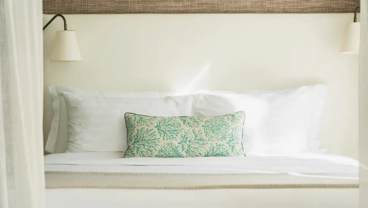 Bed with white pillows and a decorative pillow sham placed in front.