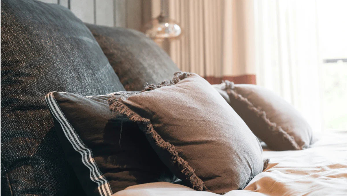 Layered neutral bedding with textured pillows in warm tones, illustrating a balanced bedroom color palette.