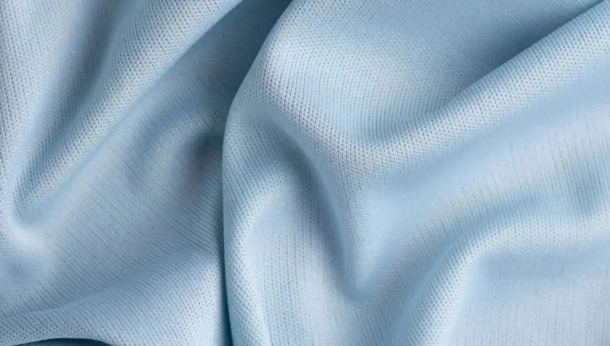 Close-up of soft light blue rayon fabric with a smooth breathable texture and gentle folds.