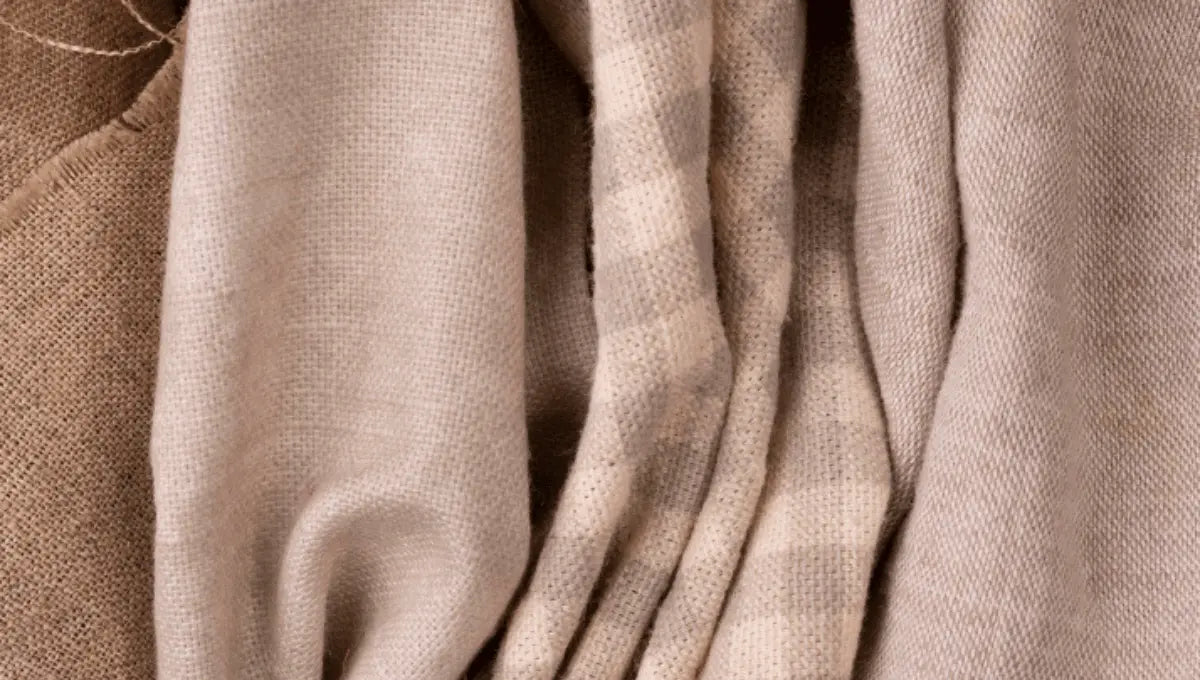 Close-up texture of soft neutral-toned European flax linen fabric folds.