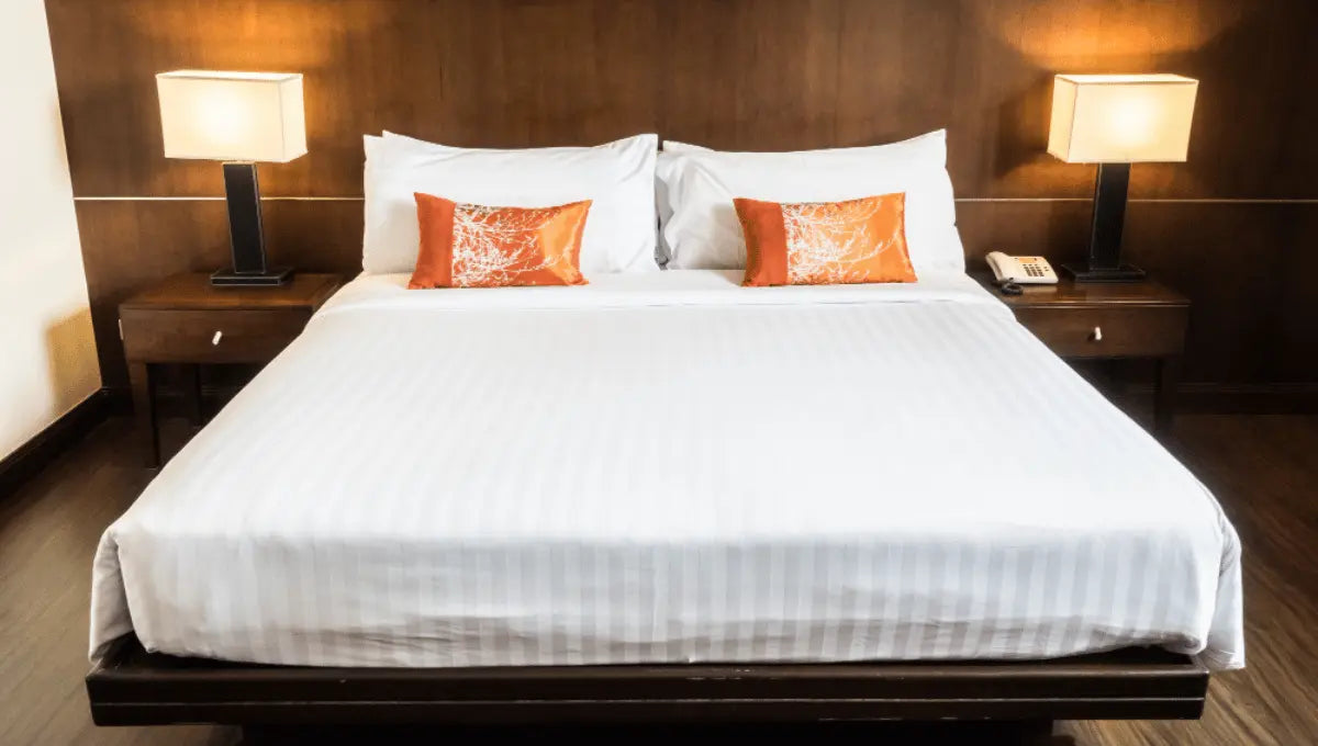 Large bed with white bedding and decorative pillows in a modern bedroom.
