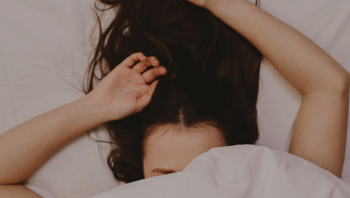 Person sleeping comfortably in bed with soft pillows and blankets, representing thoughtful sleep-related gifts.