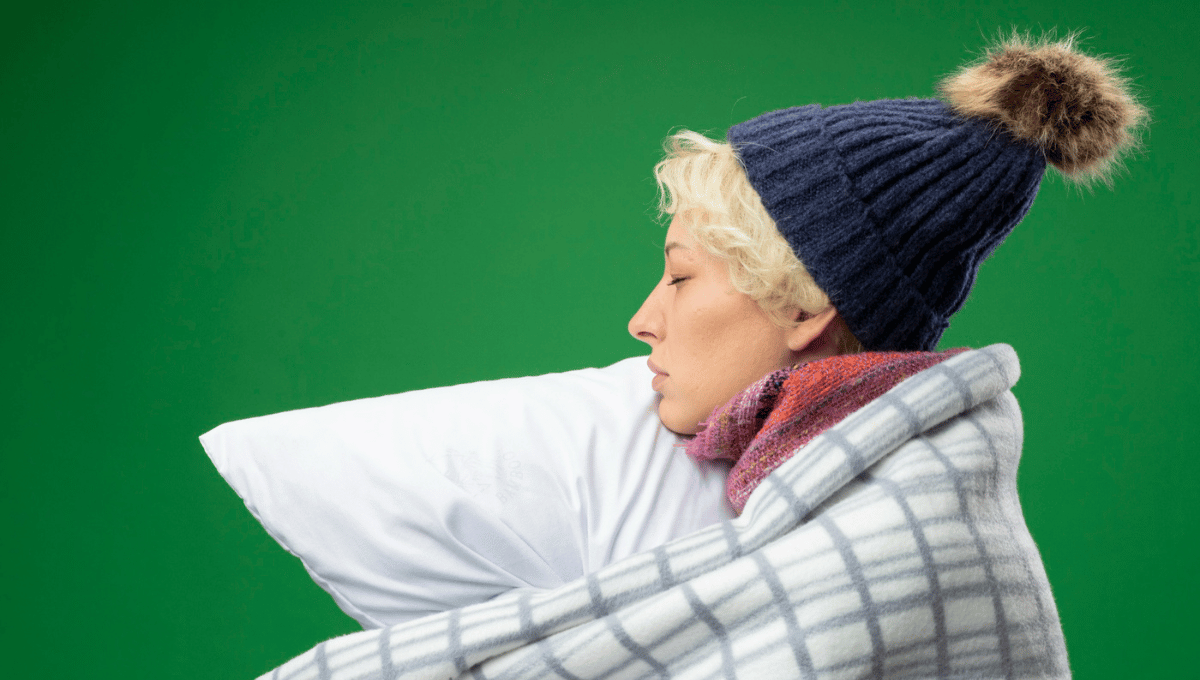 Person lying awake in bed under blankets, appearing tired and restless during winter sleep.