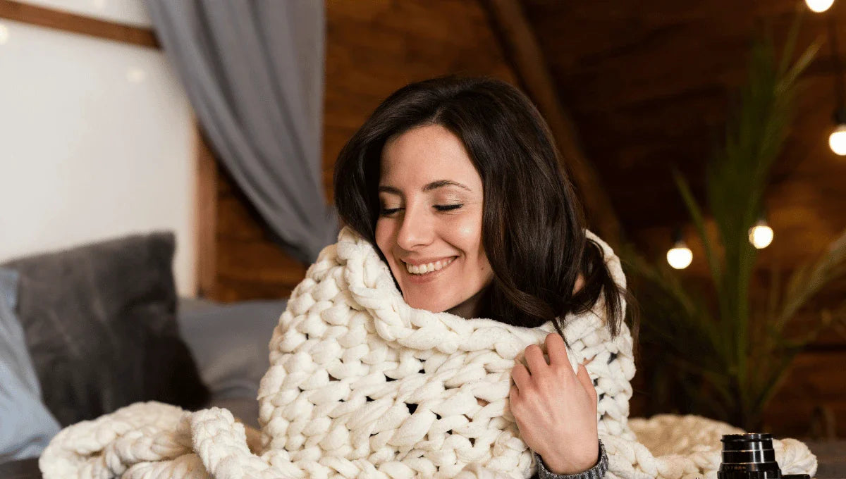 Person relaxing on a sofa while reading, surrounded by soft pillows, creating a peaceful winter solstice atmosphere.