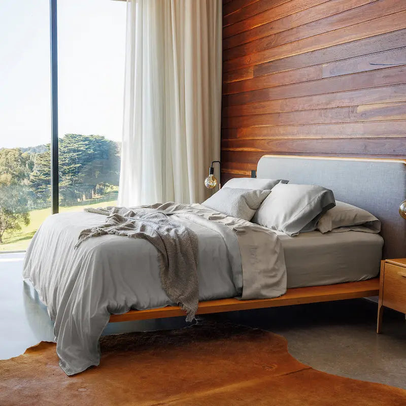 Modern bedroom with wooden bed, wooden wall, and large window view. 