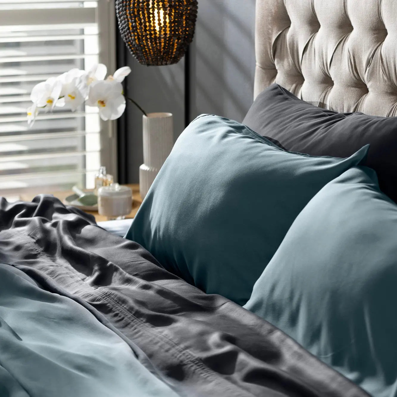 Bed with teal bedding and gray pillows in a bedroom setting. 